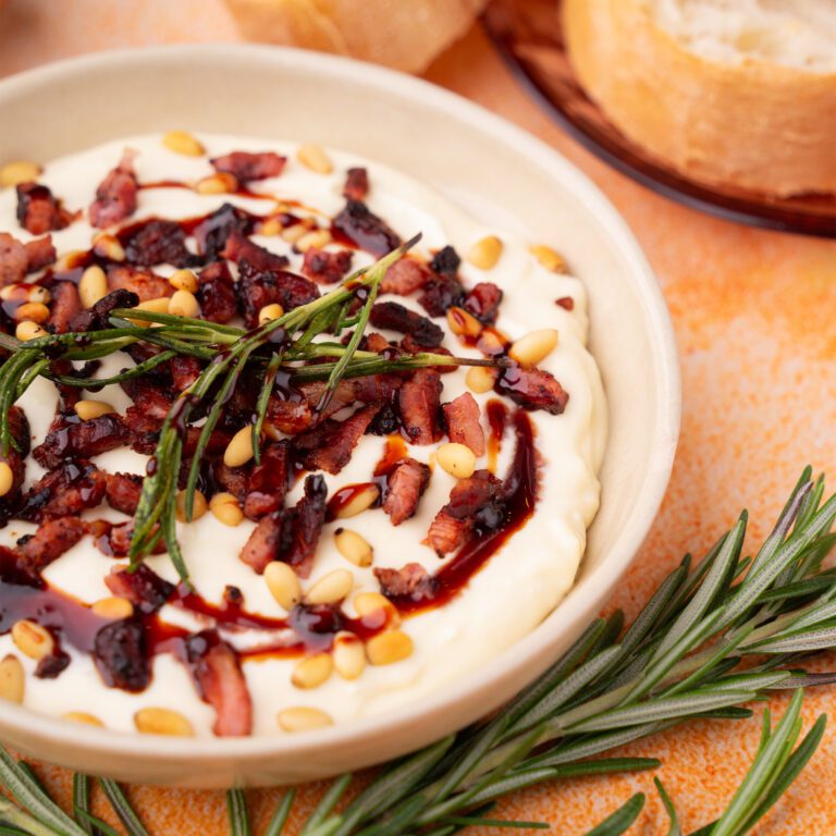 Creamy Camembert cheese dip with bacon bits, pine nuts, rosemary and a drizzle of date syrup on top.