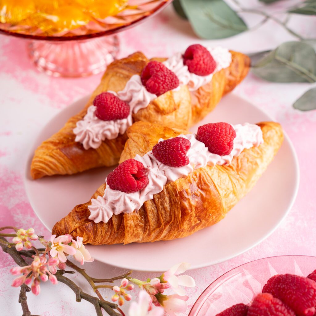 Croissants filled with pink cream and topped with raspberries.